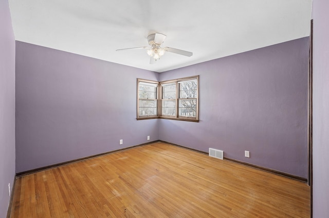 spare room featuring visible vents, baseboards, wood finished floors, and a ceiling fan