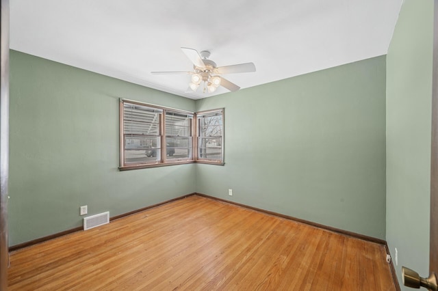 spare room with visible vents, ceiling fan, baseboards, and wood finished floors