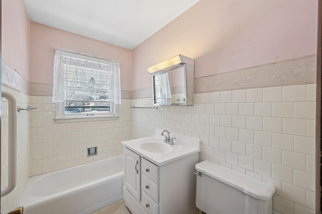 bathroom featuring toilet, tile walls, wainscoting, a bath, and vanity