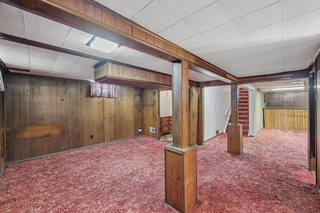 finished below grade area featuring stairway, visible vents, wood walls, and carpet floors