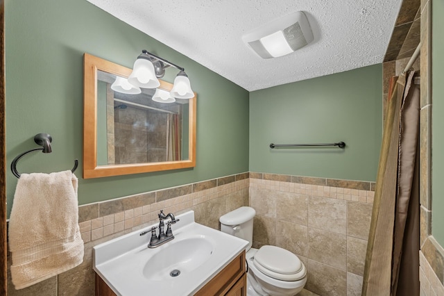 full bathroom with tile walls, toilet, wainscoting, a textured ceiling, and vanity