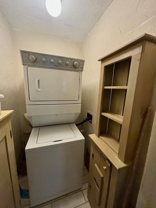 laundry area with stacked washer / dryer, a textured ceiling, and cabinets