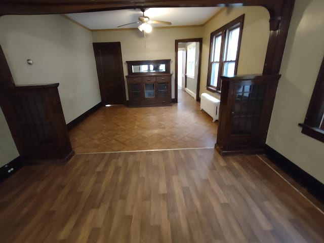 interior space featuring ceiling fan, hardwood / wood-style flooring, ornamental molding, and radiator heating unit