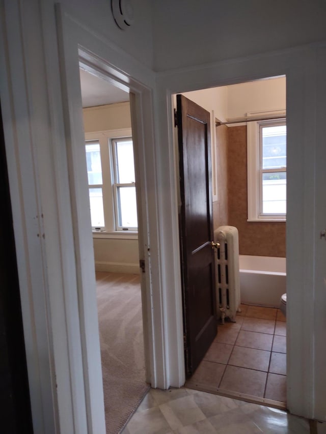 bathroom with radiator, toilet, tile patterned floors, and shower / washtub combination