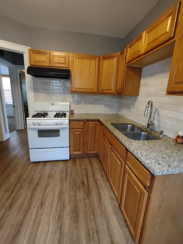 kitchen featuring tasteful backsplash, sink, light wood-type flooring, and gas range gas stove