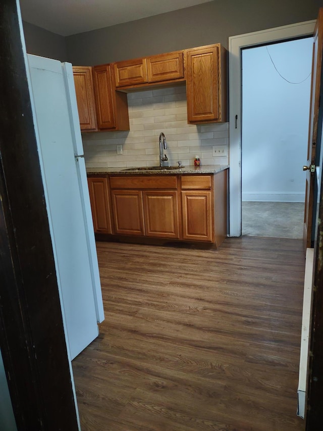 kitchen with decorative backsplash, light stone countertops, sink, and dark wood-type flooring