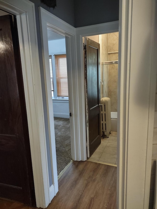 hallway with wood-type flooring and radiator