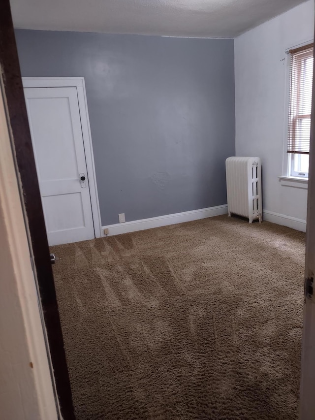 unfurnished room with carpet flooring and radiator