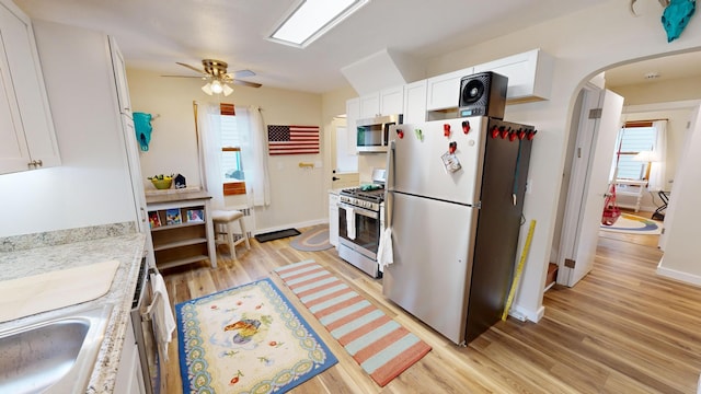 kitchen featuring stainless steel appliances, light hardwood / wood-style flooring, and white cabinets