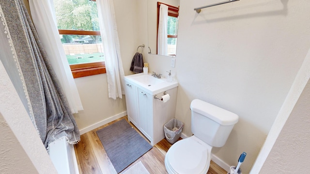 bathroom with toilet, sink, wood-type flooring, and plenty of natural light