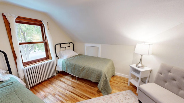 bedroom featuring radiator, hardwood / wood-style flooring, and vaulted ceiling