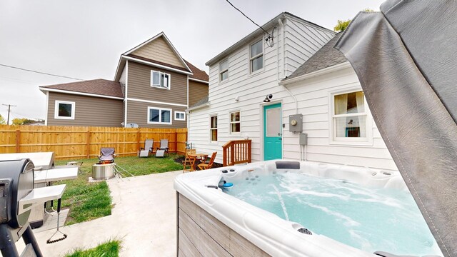 rear view of house featuring a patio and a hot tub