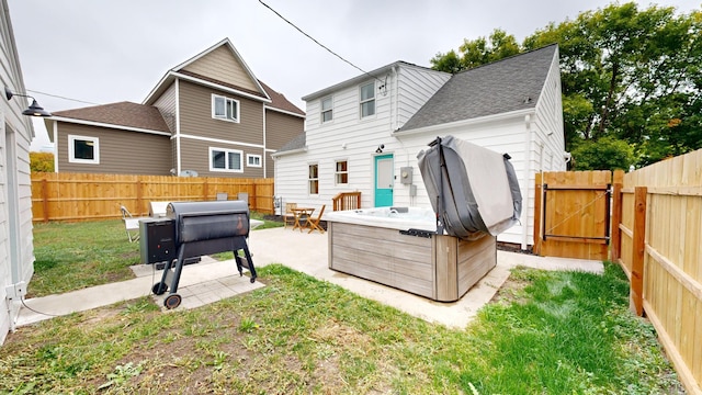 back of house with a hot tub, a lawn, and a patio area