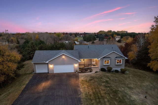 view of front of house with a garage, a front yard, covered porch, and driveway