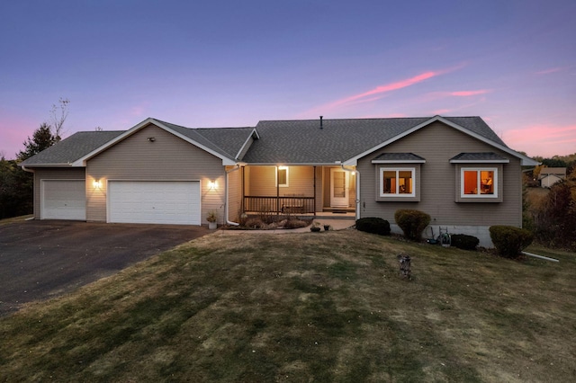 single story home featuring a porch, a garage, driveway, a lawn, and roof with shingles