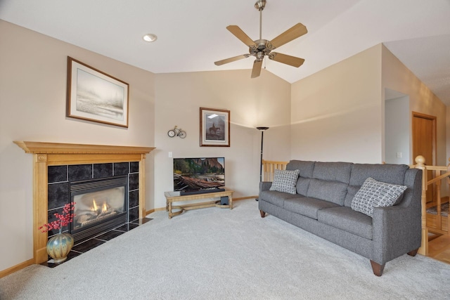 living room with lofted ceiling, a ceiling fan, carpet flooring, a tile fireplace, and baseboards