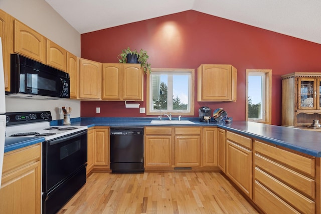 kitchen featuring light wood finished floors, vaulted ceiling, black appliances, light brown cabinets, and a sink