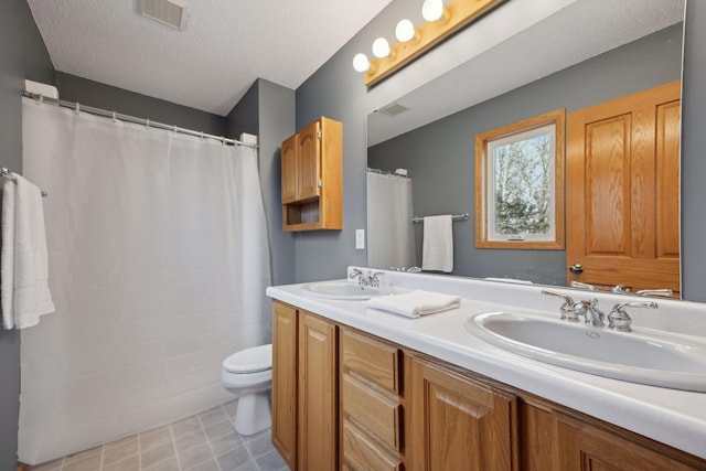 bathroom with toilet, a textured ceiling, a sink, and visible vents