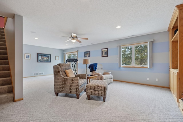 sitting room with baseboards, a healthy amount of sunlight, stairway, and a textured ceiling