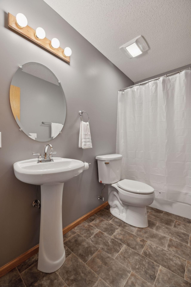 full bath with a textured ceiling, a shower with shower curtain, toilet, and baseboards