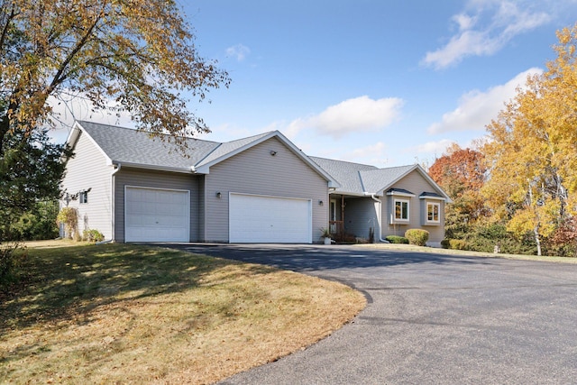 single story home featuring a garage, driveway, a front lawn, and roof with shingles