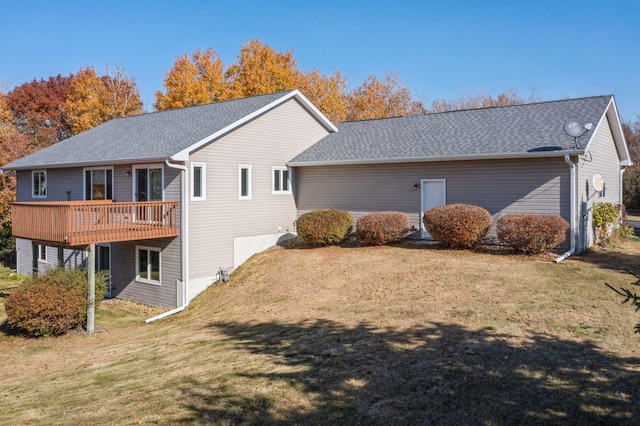 back of property featuring a shingled roof, a yard, and a deck