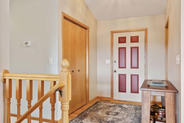 foyer with a textured ceiling, light wood-type flooring, and baseboards