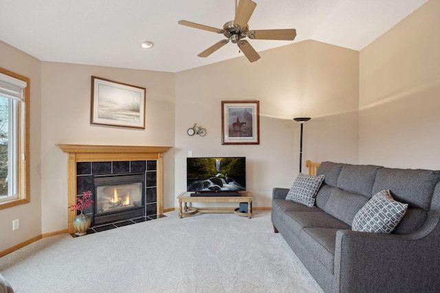 living room featuring baseboards, a ceiling fan, a tile fireplace, lofted ceiling, and carpet flooring