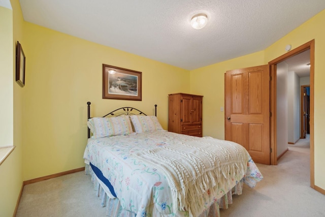 bedroom featuring light colored carpet, a textured ceiling, and baseboards