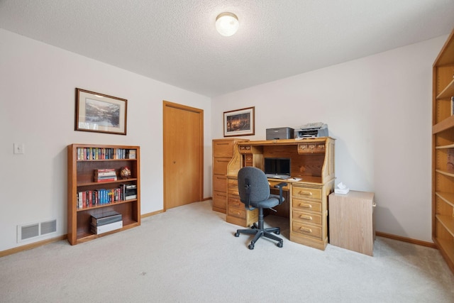 office space with a textured ceiling, baseboards, visible vents, and light colored carpet