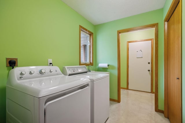 laundry area with laundry area, baseboards, a textured ceiling, and washing machine and clothes dryer