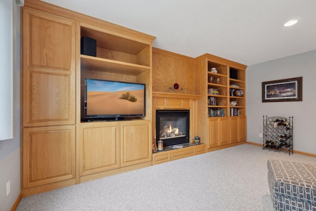 carpeted living room with recessed lighting, a glass covered fireplace, and baseboards