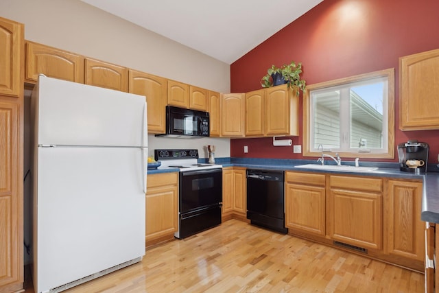 kitchen with lofted ceiling, dark countertops, light wood-type flooring, black appliances, and a sink