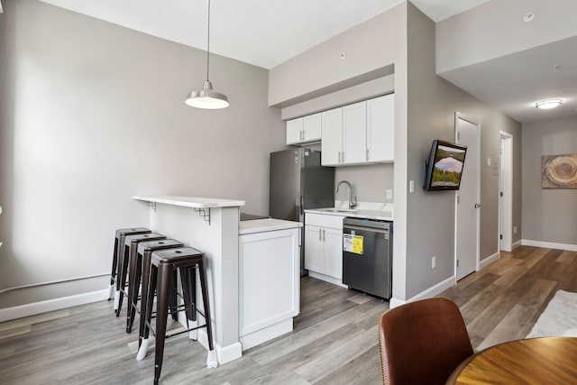 kitchen with white cabinets, a breakfast bar area, stainless steel dishwasher, pendant lighting, and sink