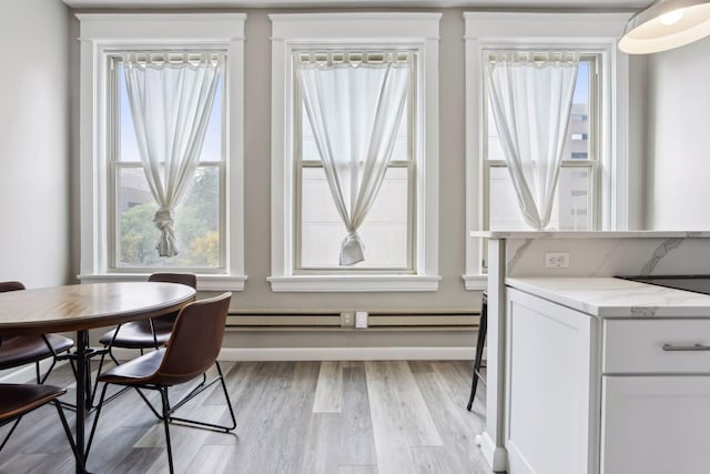 dining space with baseboard heating and light hardwood / wood-style floors