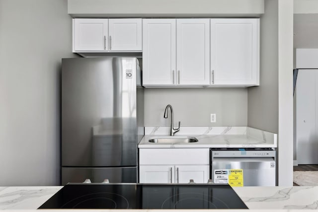 kitchen with sink, appliances with stainless steel finishes, light stone counters, and white cabinets