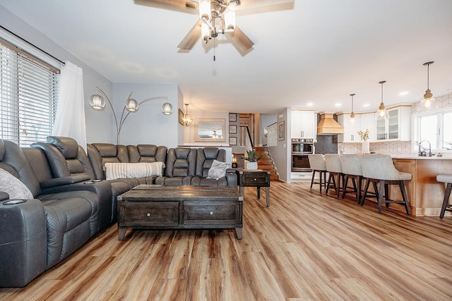 living room with ceiling fan, sink, and light hardwood / wood-style floors