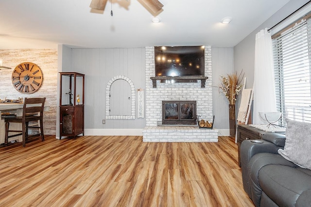 living room featuring a fireplace, plenty of natural light, light hardwood / wood-style floors, and ceiling fan