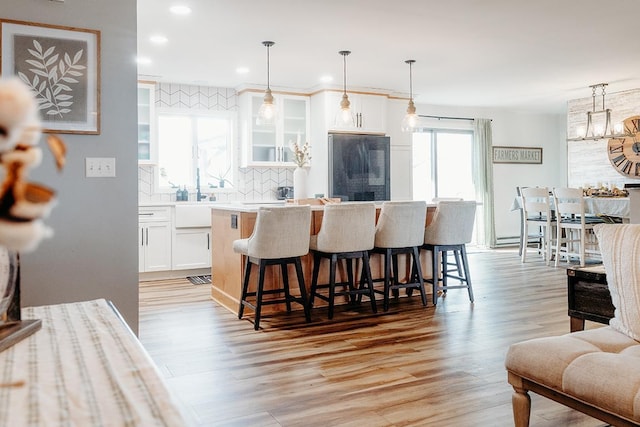 kitchen featuring black refrigerator, decorative light fixtures, a breakfast bar area, and white cabinets