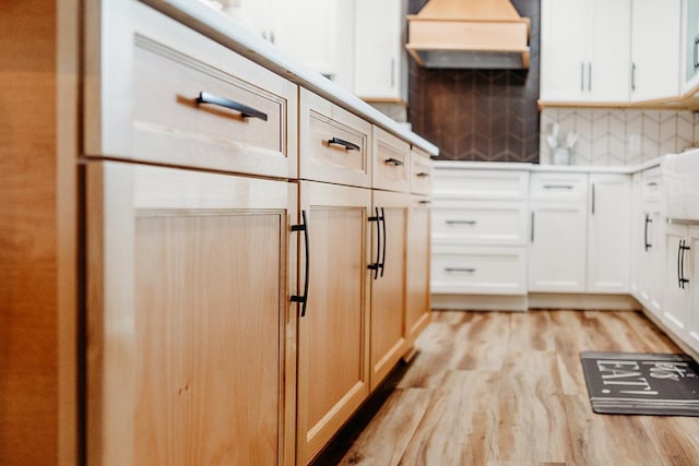 kitchen with tasteful backsplash, white cabinetry, and light hardwood / wood-style floors