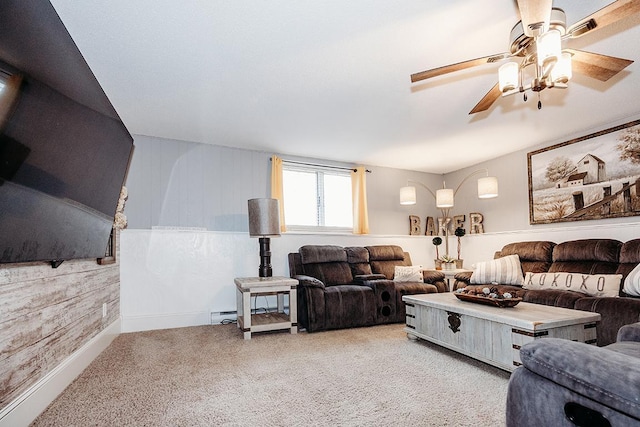 living room featuring ceiling fan, light colored carpet, wood walls, and a baseboard heating unit