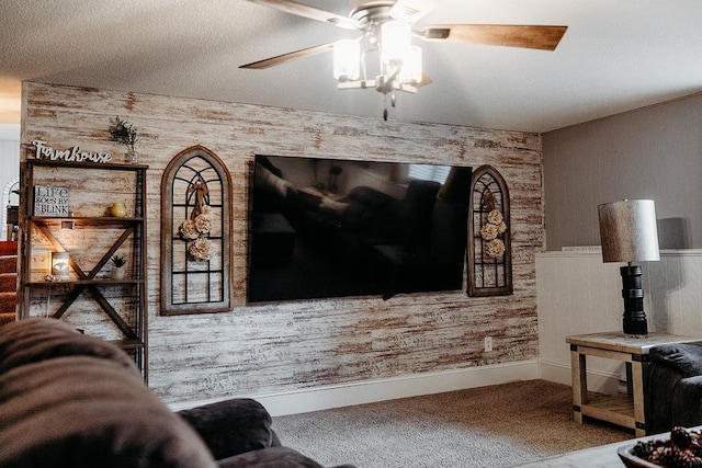 living room with ceiling fan, carpet floors, and a textured ceiling