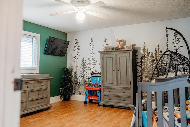 bedroom with ceiling fan, light hardwood / wood-style floors, and a textured ceiling