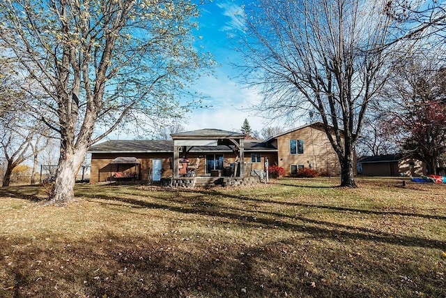 rear view of property featuring a gazebo and a lawn