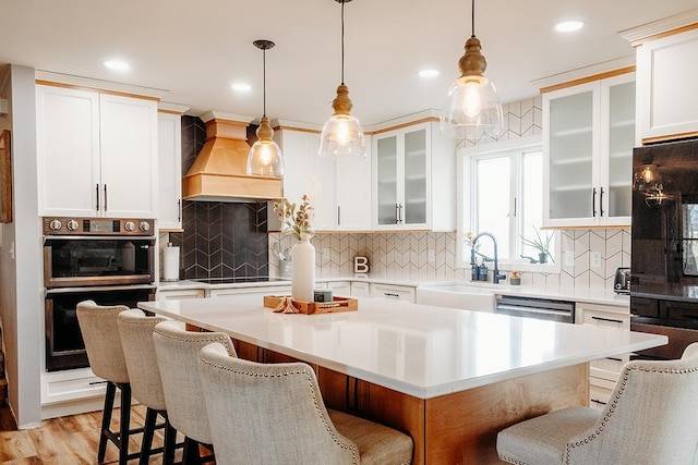 kitchen with multiple ovens, a kitchen breakfast bar, a center island, and custom exhaust hood