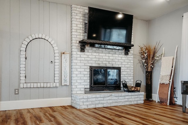 unfurnished living room with hardwood / wood-style flooring and a brick fireplace