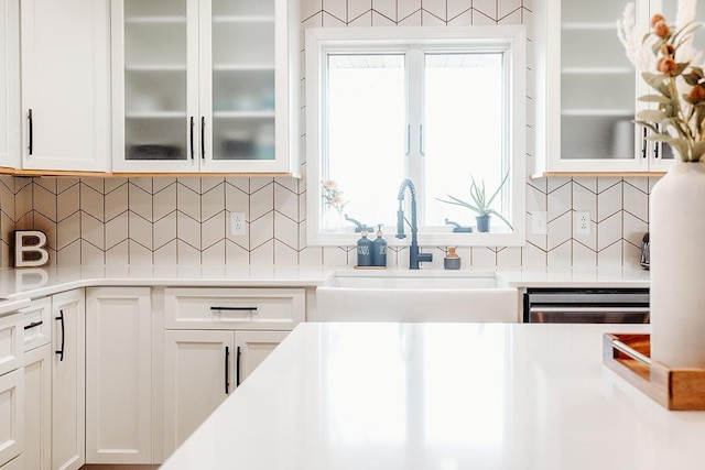 kitchen with dishwasher, sink, white cabinets, and decorative backsplash