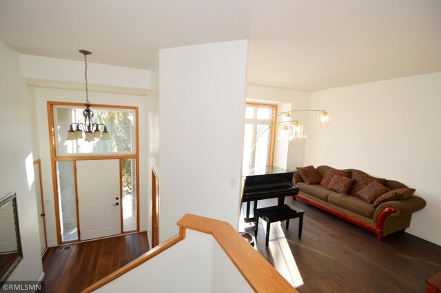 entryway featuring a chandelier, plenty of natural light, and dark wood-type flooring