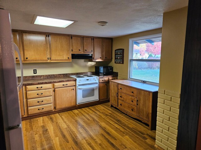 kitchen with range hood, a textured ceiling, refrigerator, light hardwood / wood-style floors, and white range with electric stovetop