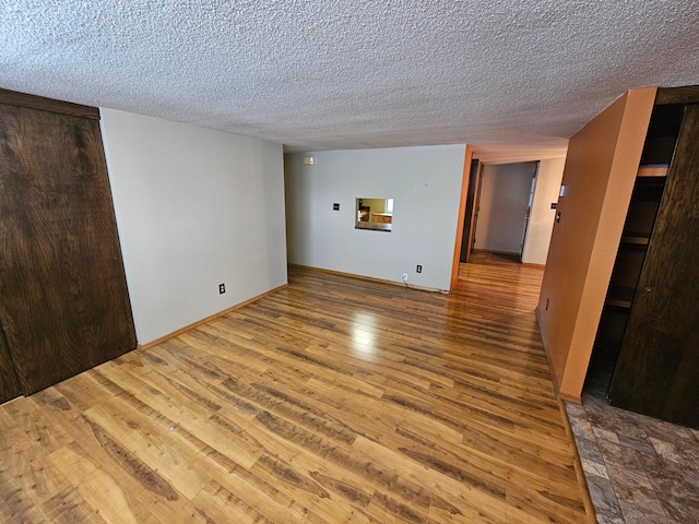 empty room with a textured ceiling and wood-type flooring